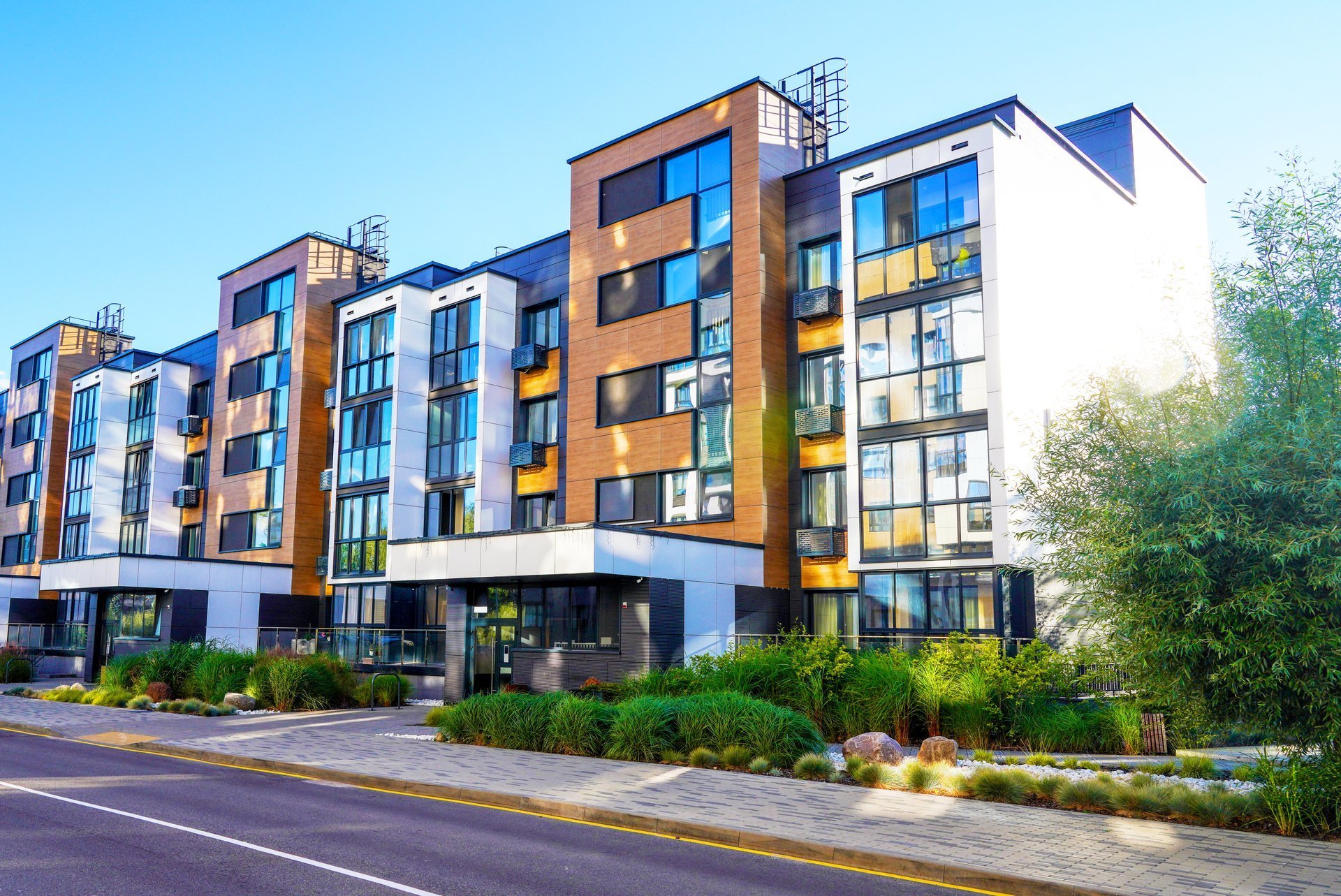 Modern residential building in contemporary architecture. Landscaping for urban spaces. Modern apartment Facade in green environment.
