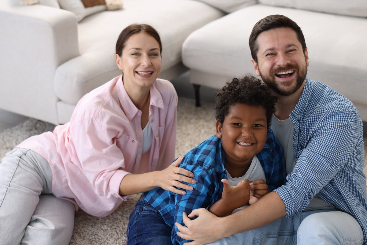 Happy adoptive parents embracing child at home representing Turkish citizenship acquisition through legal adoption for foreign adopted children